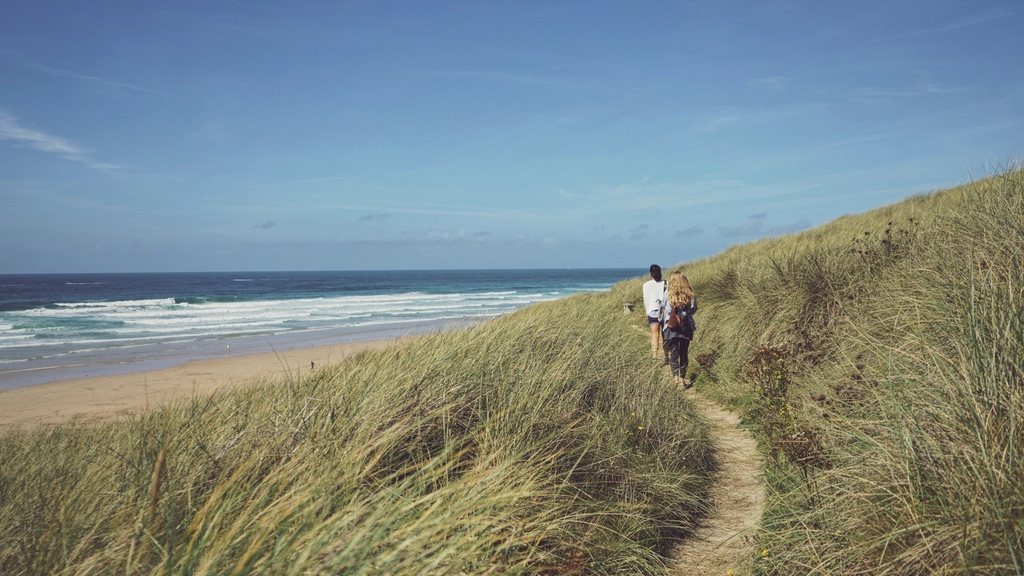 Twee mensen wandelen over een pad door de duinen langs zee